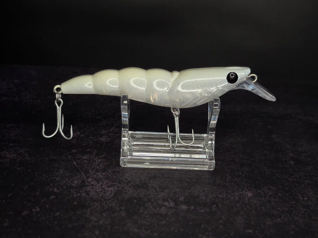 A white and translucent hard bait fishing lure with 2 treble hooks, displayed on a clear acrylic stand against a dark background.
