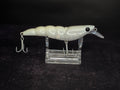 A white and translucent hard bait fishing lure with 2 treble hooks, displayed on a clear acrylic stand against a dark background.