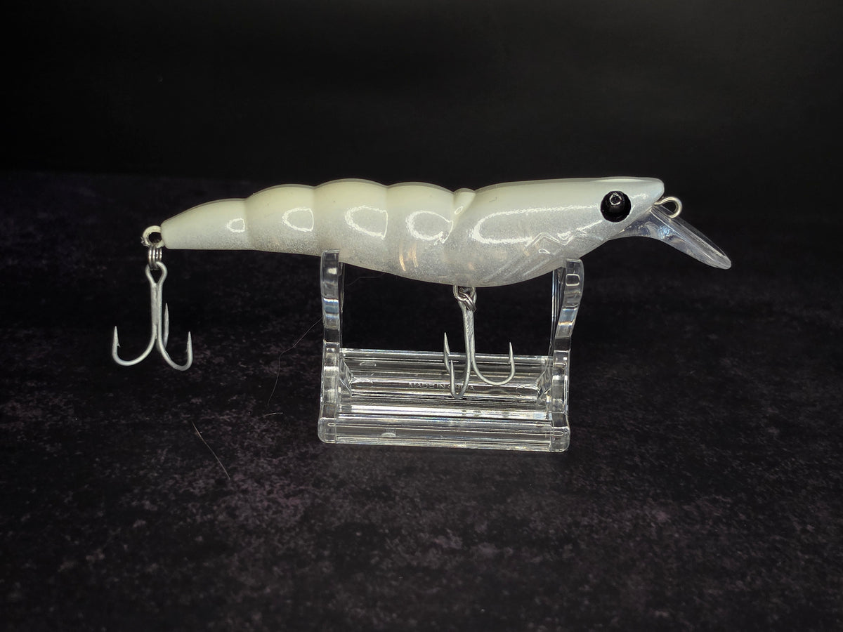 A white and translucent hard bait fishing lure with 2 treble hooks, displayed on a clear acrylic stand against a dark background.