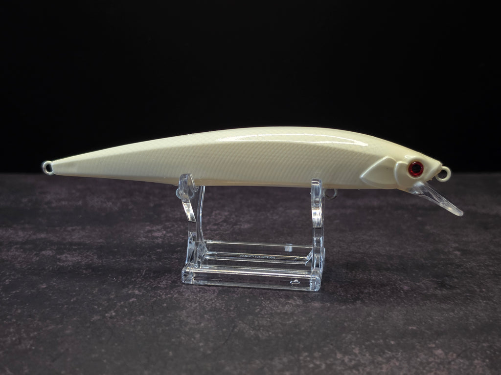A cream-colored hard fishing lure with a red eye and clear diving lip, displayed on a clear acrylic stand against a dark background.