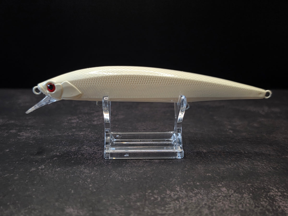 A cream-colored hard fishing lure with a red eye and clear plastic diving lip, displayed on a clear acrylic stand against a dark background.