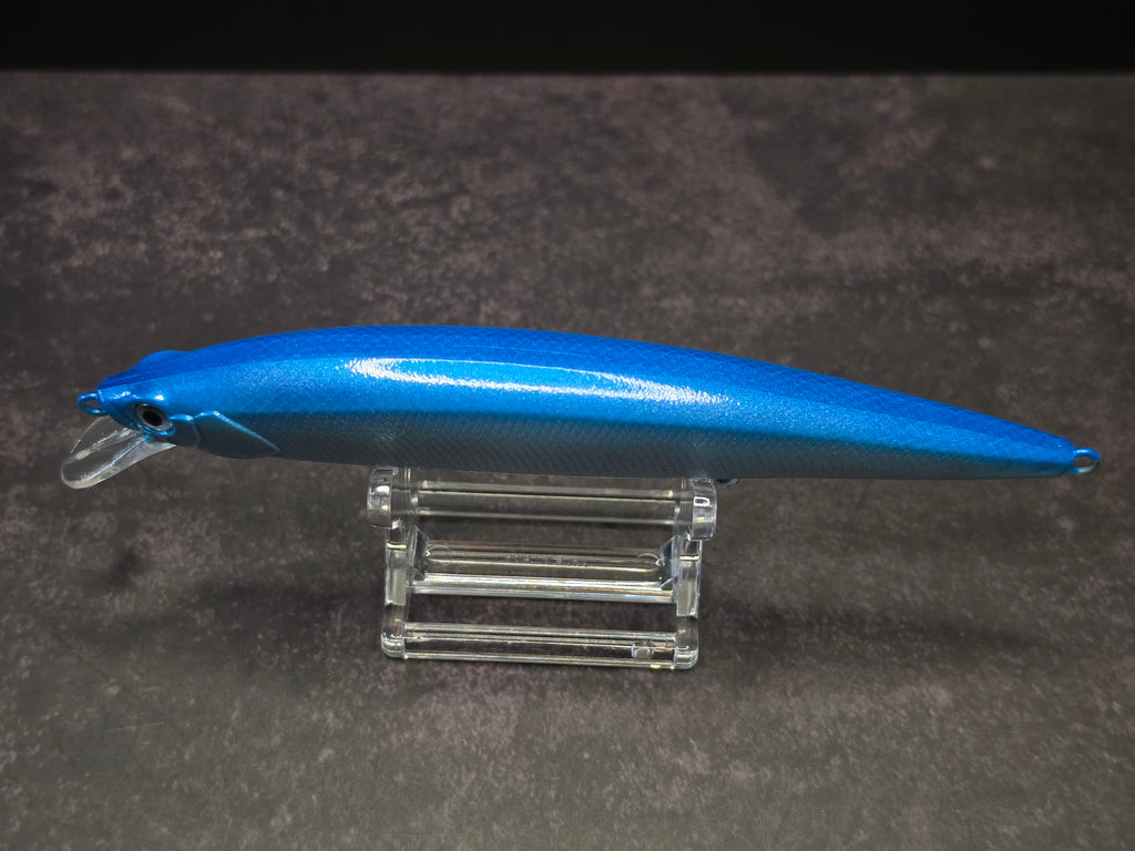 A blue hard bait fishing lure with a clear plastic diving lip, displayed on a clear acrylic stand against a dark background.
