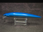 A blue hard bait fishing lure with a clear plastic diving lip, displayed on a clear acrylic stand against a dark background.