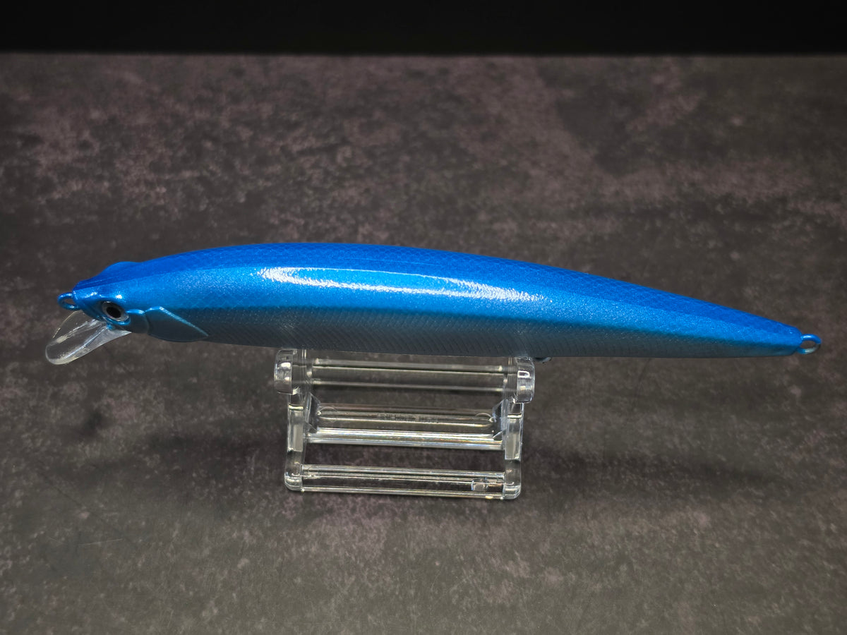 A blue hard bait fishing lure with a clear plastic diving lip, displayed on a clear acrylic stand against a dark background.