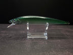 A green metallic fishing lure with a clear plastic diving lip, displayed on a clear acrylic stand against a dark background.