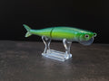 Dark green to light green gradient colored fish shaped moon bill glide bait on a clear acrylic stand against a black and gray background. 